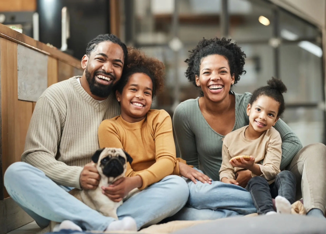 Happy family of four smiling at home with their pet dog.