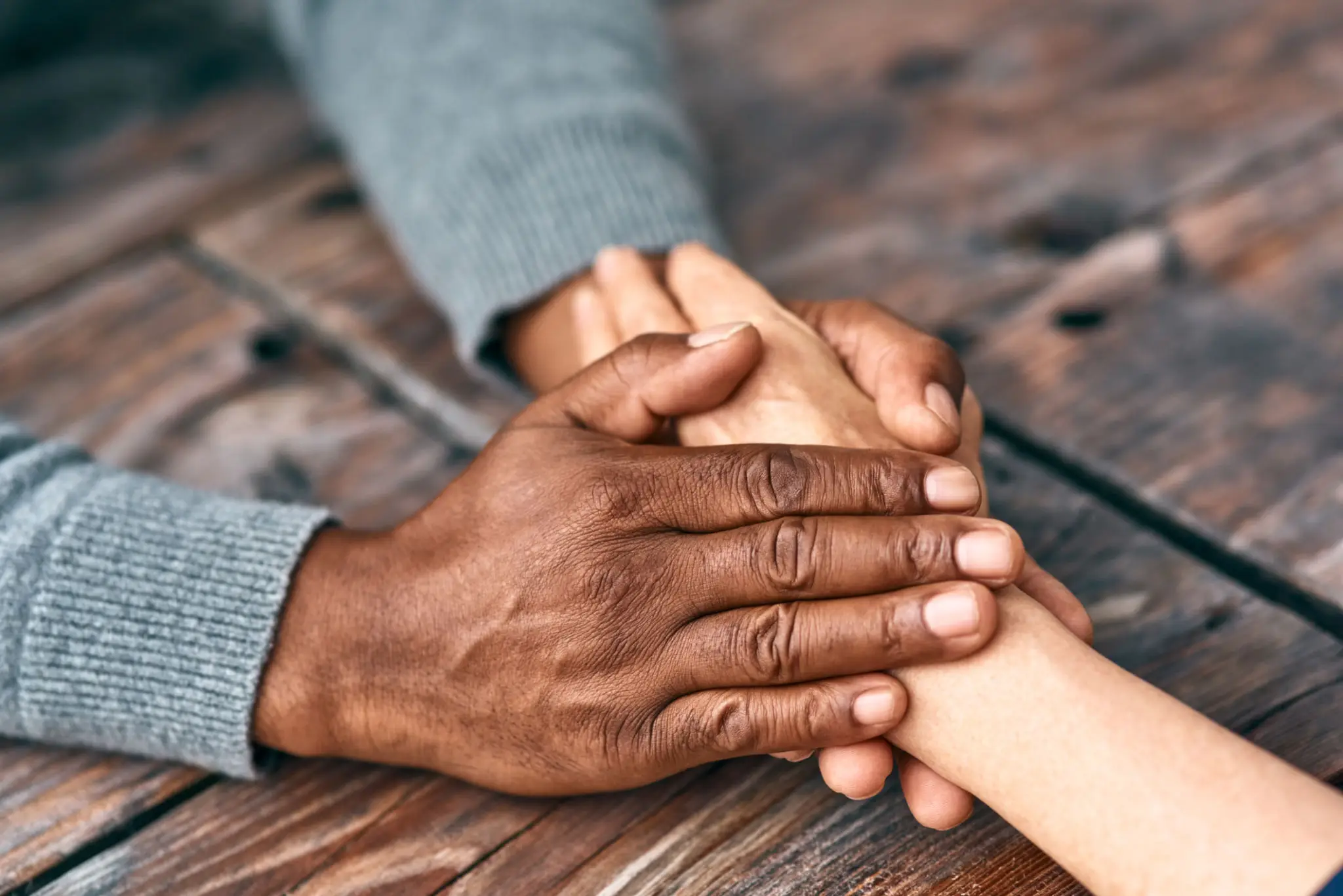 Two hands gently holding each other in a comforting gesture.